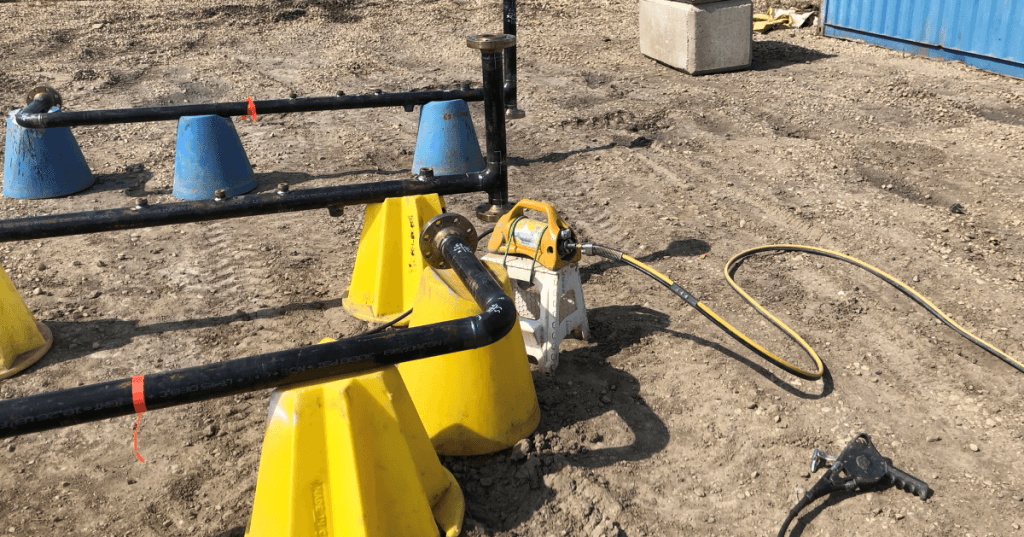 Industrial pipe spools staged for radiographic weld inspection with a Delta 880 exposure device visible